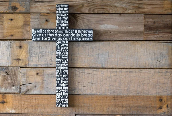 Black wooden cross  the Lord\'s prayer  on the shabby  natural wooden  plank close-up.