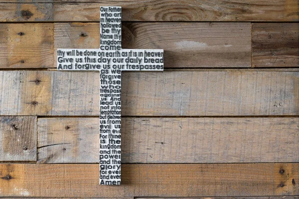 White wooden cross with the Lord\'s prayer on the shabby  wooden  plank background.