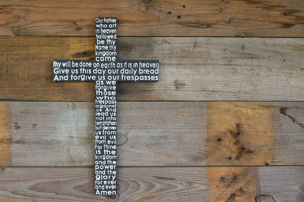 Black wooden cross  the Lord's prayer  on the shabby  natural wooden  plank close-up. — Stock Photo, Image