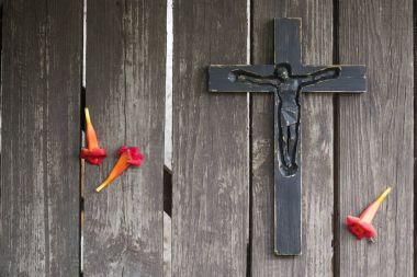 Kırmızı çiçekli eski püskü ahşap tahta üzerinde siyah tahta haç.