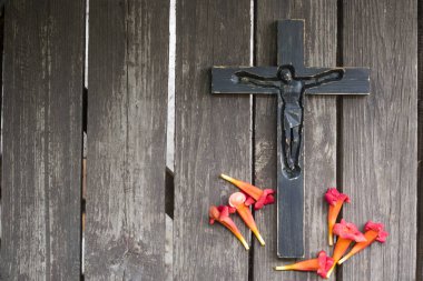 Kırmızı çiçekli eski püskü ahşap tahta üzerinde siyah tahta haç.