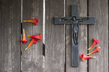 Kırmızı çiçekli eski püskü ahşap tahta üzerinde siyah tahta haç.