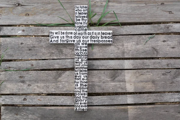 White wooden cross with the Lord\'s prayer  on weathered wooden  plank background.