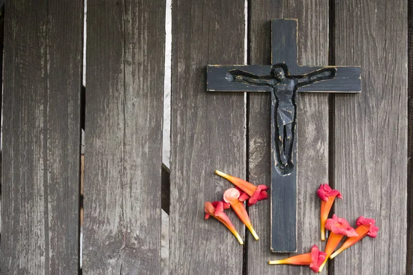 Kırmızı çiçekli eski püskü ahşap tahta üzerinde siyah tahta haç.