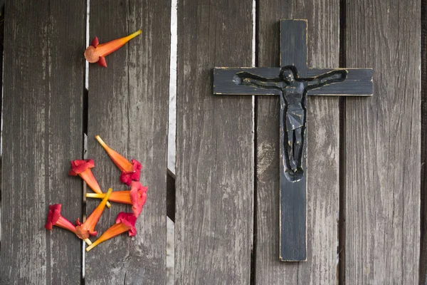 Kırmızı çiçekli eski püskü ahşap tahta üzerinde siyah tahta haç.