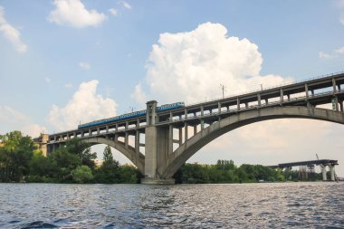 Bir tren köprüden mavi gökyüzü karşı bir nehir üzerinde sürme