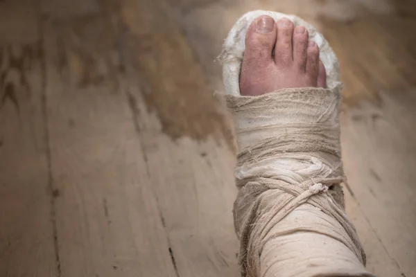 Broken leg in plaster on a shabby wooden floor