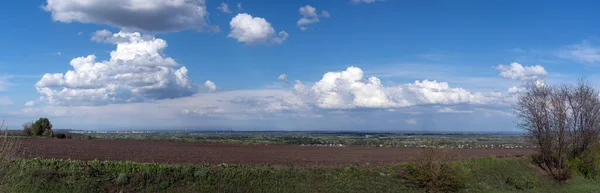 Paisaje rural tranquilo, vista panorámica. Campo negro vacío, prados verdes y pueblo sobre fondo azul del cielo — Foto de Stock