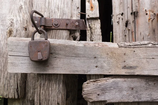 Detail, old rusty padlock on broken wooden barn doors