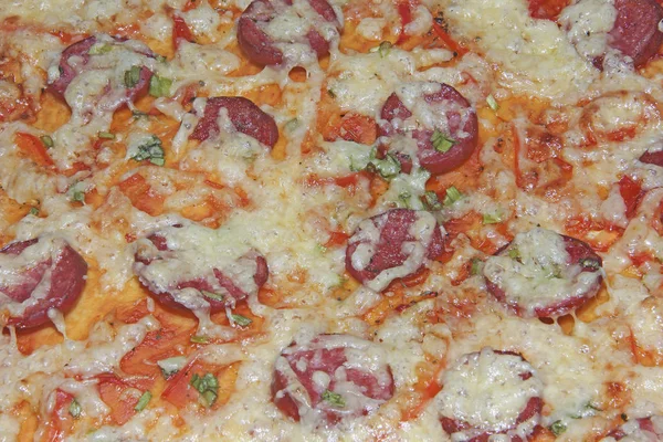 Bitmiş pizzanın dokusu erimiş peynir ve füme sosis ile üst katmanın dokusudur. Mutfak tabağı pişirme süreci.