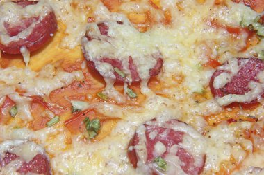 Bitmiş pizzanın dokusu erimiş peynir ve füme sosis ile üst katmanın dokusudur. Mutfak tabağı pişirme süreci.