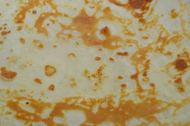 Yemeğin dokusu bej-kahverengi tonlar, Maslenitsa bayramı için yapılan kreplerdeki kıvrımlı desenler..