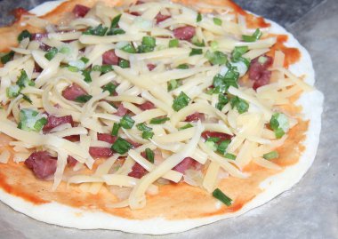 Bitmiş pizzanın dokusu erimiş peynir ve füme sosis ile üst katmanın dokusudur. Mutfak tabağı pişirme süreci.