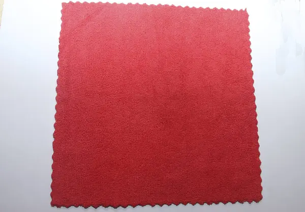 Concept of cleaning of premises, offices and houses. Tools for restoring order and cleanliness. A red microfiber rag with scalloped edges.