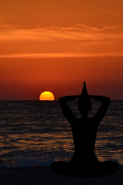 Silhouette einer jungen Frau, die am Strand bei Sonnenaufgang Yoga praktiziert — Stockfoto