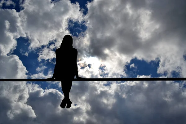 Silhueta menina sentado contra céu nublado — Fotografia de Stock