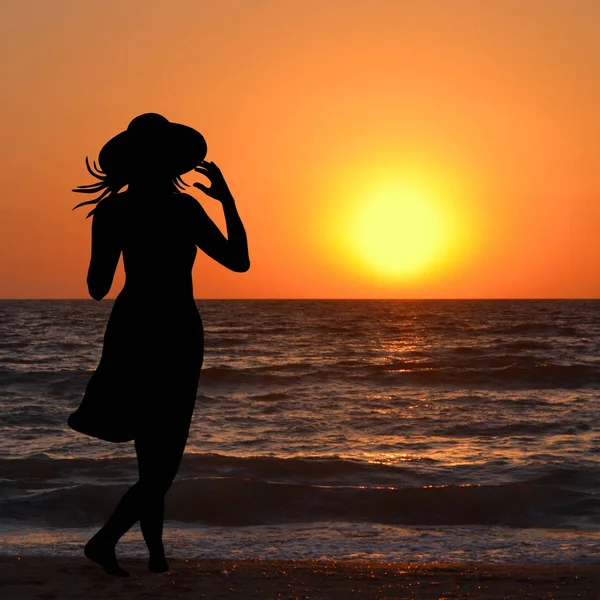 Женщина в шляпе смотрит на восход солнца — стоковое фото