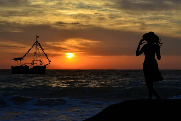 Вид ззаду на силует жінки, що спостерігає за човном на сході сонця — стокове фото