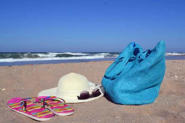 Zomer concept met tas, hoed, bril en flip flops op strand — Stockfoto