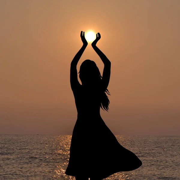 Silhueta de jovem segurando o sol em suas mãos — Fotografia de Stock