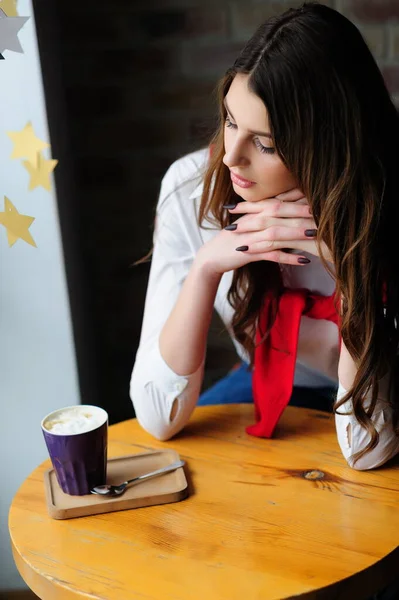 コーヒーを飲みながらカフェの窓のそばのテーブルの女の子 — ストック写真