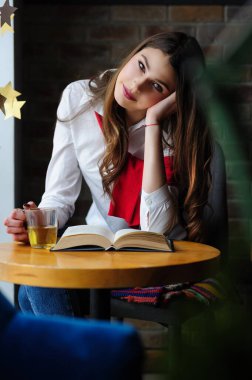 Kafenin penceresinin yanındaki masada bir fincan çay ve bir kitapla bir kız.