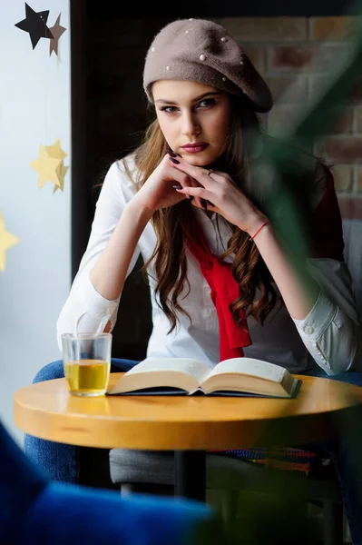 お茶と本が入ったカフェの窓辺のテーブル席の女の子 — ストック写真
