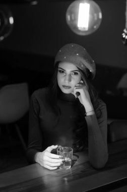 Masada kırmızı kazaklı güzel esmer bir kızın portresi. Alacakaranlıkta bir fincan çayla.