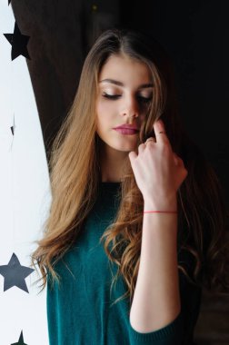 Pencerenin yanında yeşil kazaklı güzel bir esmer kızın portresi.