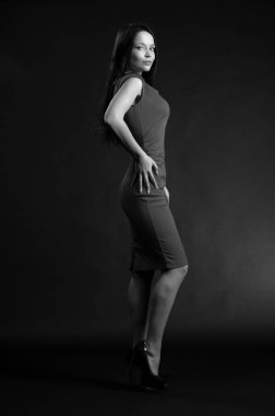 Siyah arka planda poz veren güzel, seksi esmer kız.