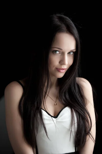 Siyah arka planda poz veren güzel, seksi esmer kız.