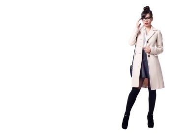 Güzel, seksi esmer kız beyaz bir arka planda poz veriyor.