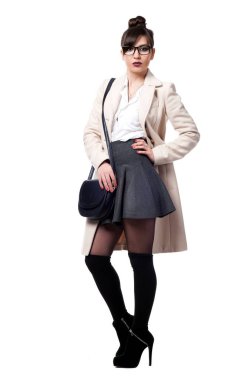 Güzel, seksi esmer kız beyaz bir arka planda poz veriyor.