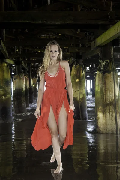 Frau in Rot unter einem Pier — Stockfoto