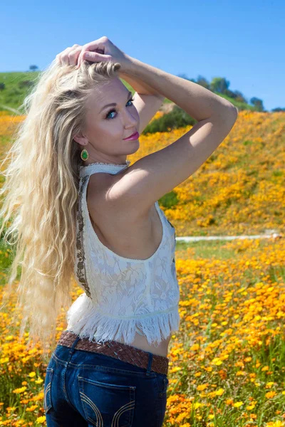 Hermosa rubia en el campo de flores — Foto de Stock