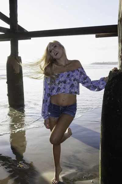 Blond girl under a pier — Stock Photo, Image