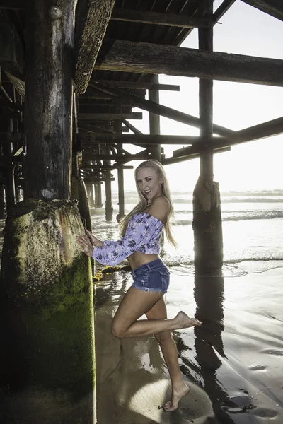 Blondes Mädchen unter einem Pier — Stockfoto