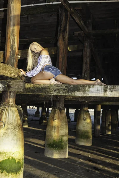 Blondes Mädchen unter einem Pier — Stockfoto