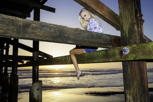 Blond girl under a pier — Stock Photo, Image