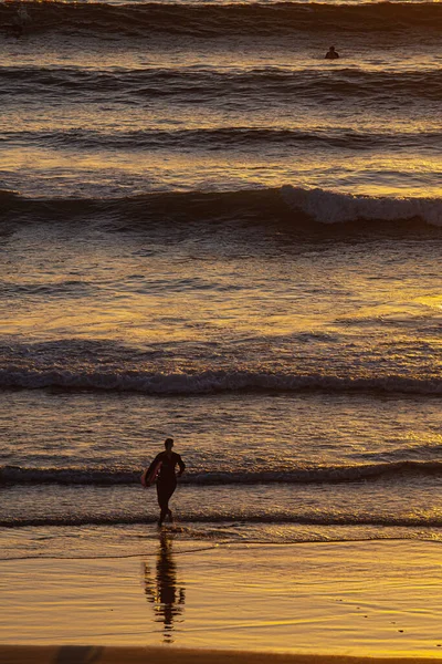 在太阳落山的时候冲浪的轮廓 — 图库照片