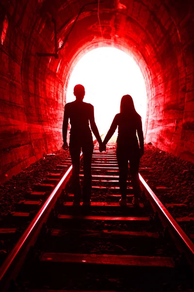 Casal apaixonado andando juntos através de um túnel ferroviário — Fotografia de Stock