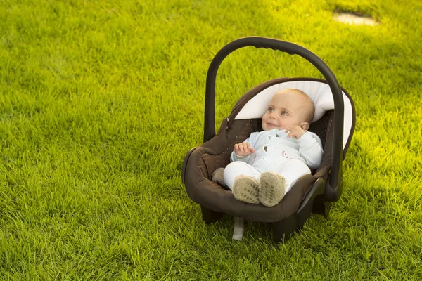 Bebê no assento do carro na grama — Fotografia de Stock
