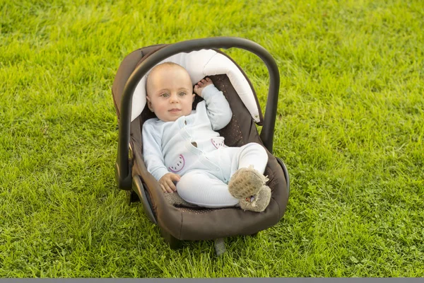 Dítě v autosedačce na trávě — Stock fotografie