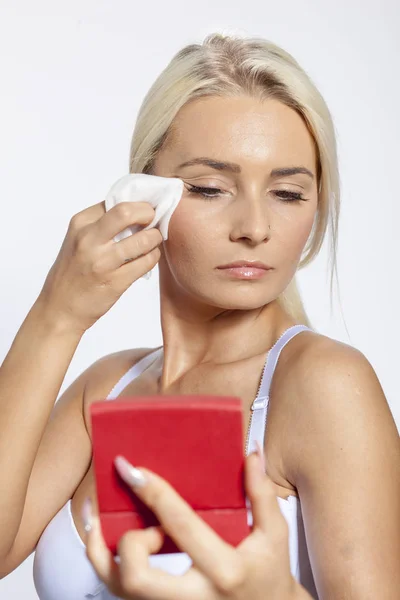 Mujer joven cara limpia con toallitas húmedas, mirando en el espejo en la mano —  Fotos de Stock