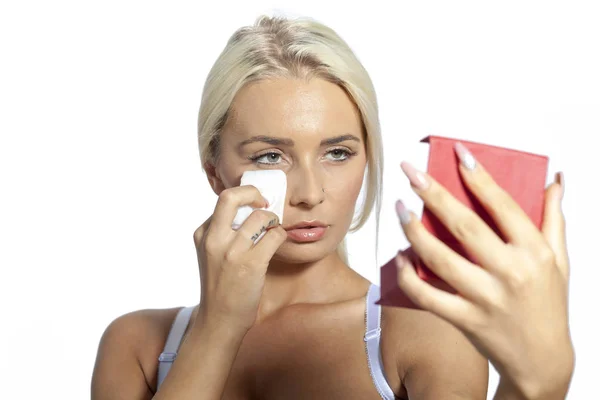 Mladá žena čistý obličej s vlhčené ubrousky, při pohledu na zrcadle v ruce — Stock fotografie