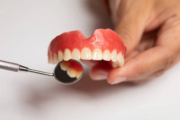 Prótese dentária em mãos de médico dentista, verificando com espelho — Fotografia de Stock