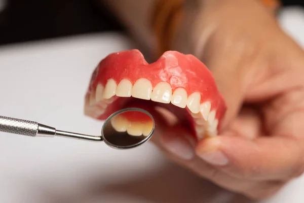 Prótese dentária em mãos de médico dentista, verificando com espelho — Fotografia de Stock