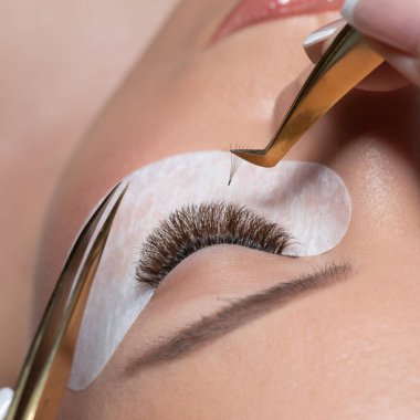 Kirpik uzatma prosedürü. Uzun kirpikli kadın gözü. Kırbaçlar. Cımbızı, makroyu, seçici odağı kapat