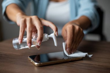 Kadın cep telefonunu ıslak mendil mendilli fotoğrafla temizliyor.