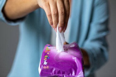 Genç kadın temizlik için antibakteriyel ıslak mendil paketini aç.